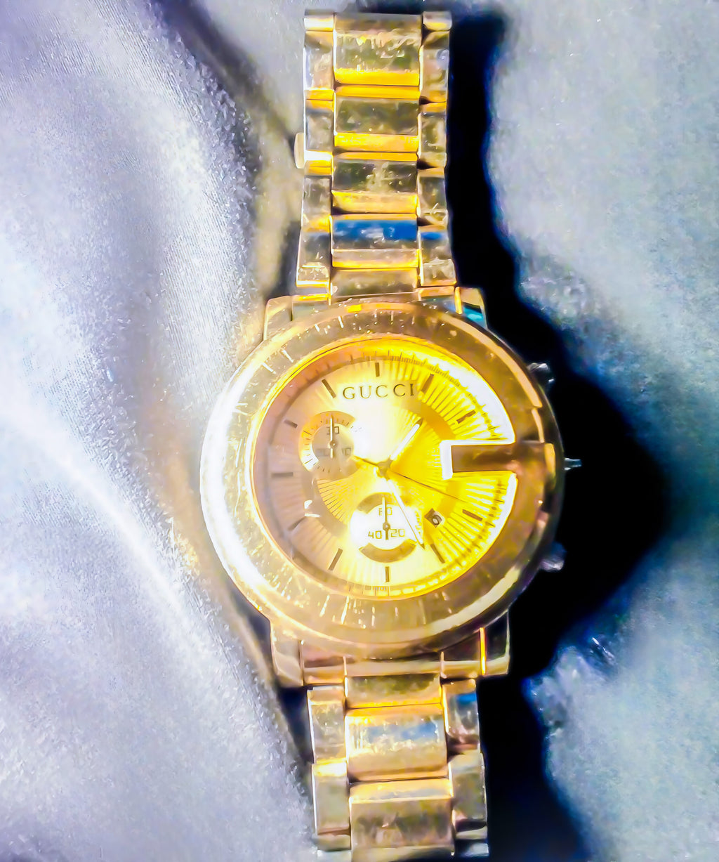 Gold Gucci watch on a textured blue surface